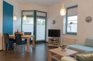 Inselblume 62 - Strandnahe Ferienwohnung am Südstrand – Esstisch mit TV und Couch im Wohnzimmer der Ferienwohnung direkt am Südstrand in Burgtiefe